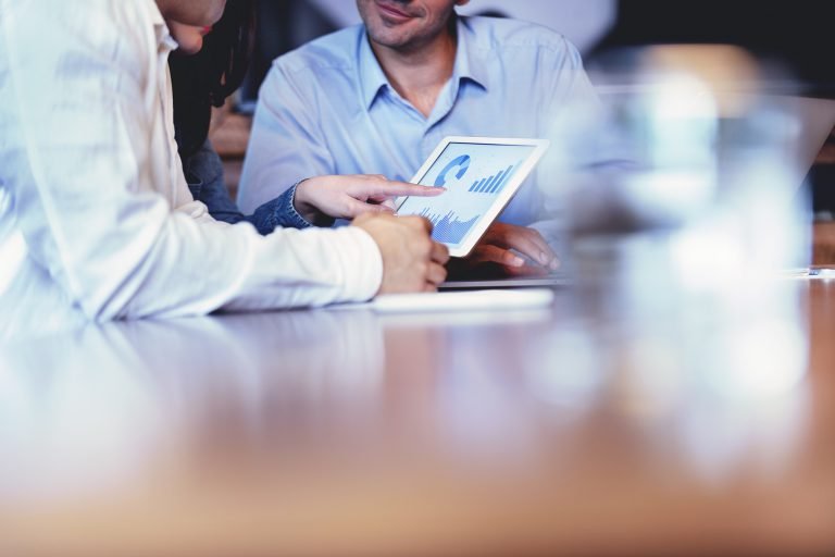 Business people working on financial data on a digital tablet. One looks like the manager working with employees, or a financial advisor. It may also be a training session. All are dressed in business casual clothing. Business people working on financial data on a digital tablet. One looks like the manager working with employees, or a financial advisor. It may also be a training session. All are dressed in business casual clothing.